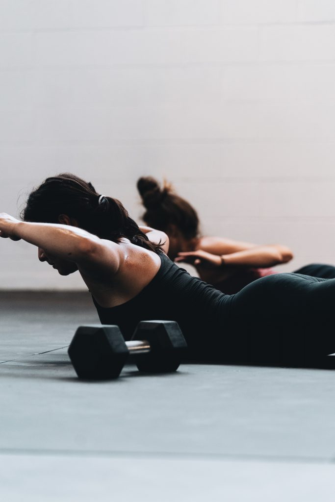 femme faisant un exercice sportif en salle, au sol de dos